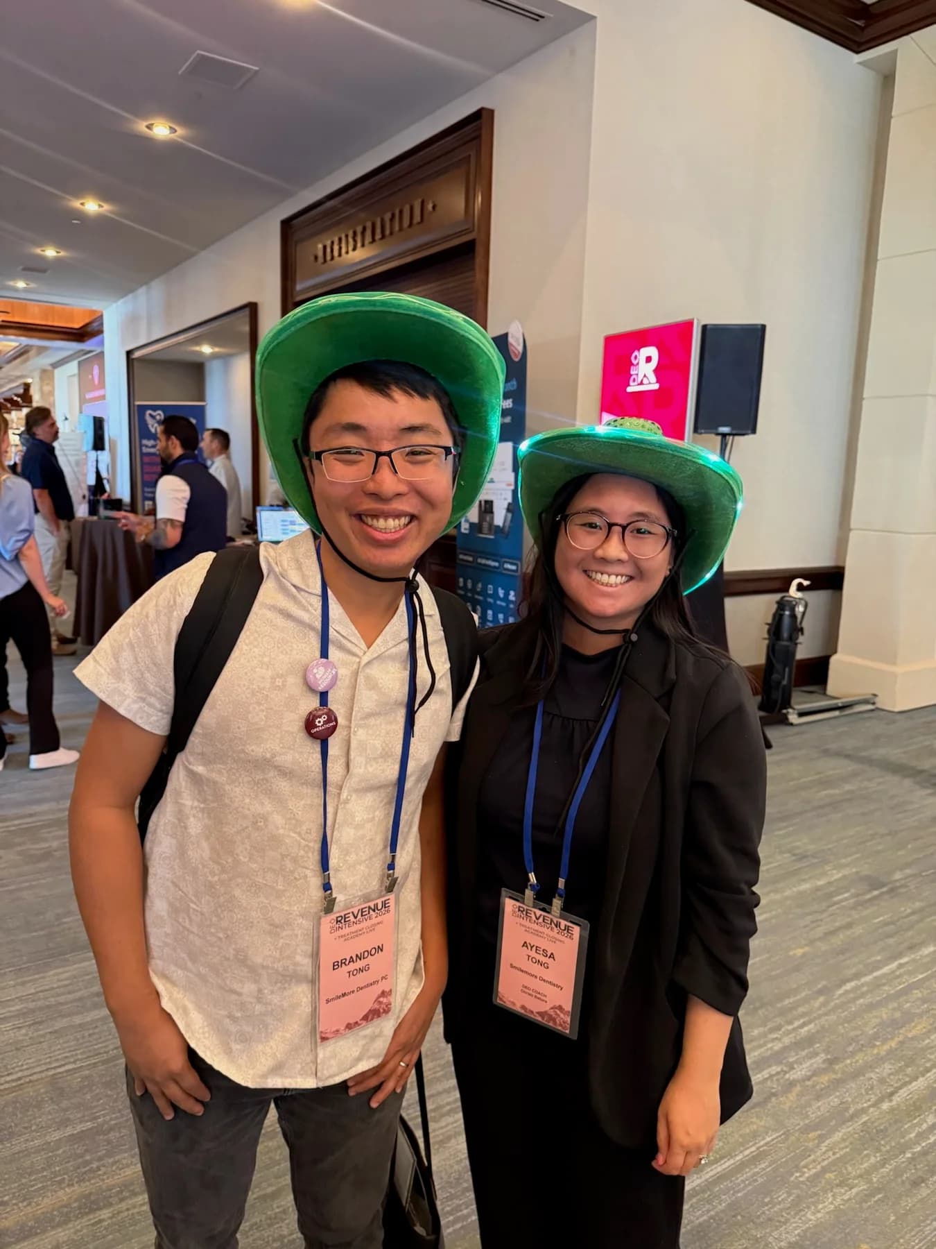 Two dental conference attendees wearing green hats at DEO Revenue Intensive